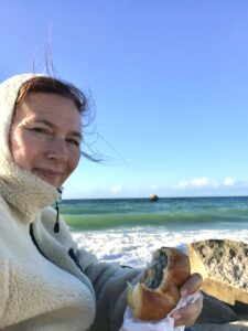Nicole (verkleidet als weißes Schaf) mit Fischbrötchen an der Ostsee